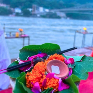 Traditional floral offering with marigolds and incense by the Holy Ganges river bank, part of the cultural experience during an aerial yoga teacher training in Rishikesh.