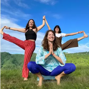 Happy yoga students posing outdoors against green hills during an aerial yoga teacher training in Rishikesh.