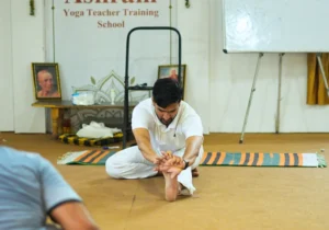 Teacher guiding a student through a traditional yoga stretch at one of the best places to learn yoga in India