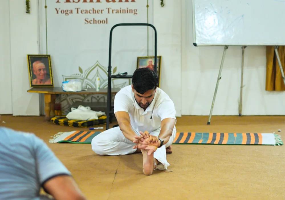 Teacher guiding a student through a traditional yoga stretch at one of the best places to learn yoga in India