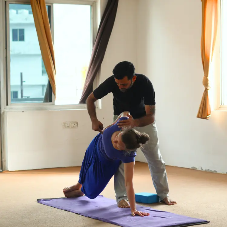Yoga teacher guiding a student through a yoga pose during Yoga Teacher Training Courses in Rishikesh