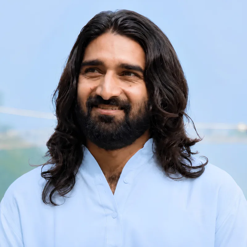 Jagjeet Singh, yoga training course teacher in Rishikesh, India, wearing traditional white attire with a peaceful mountain backdrop