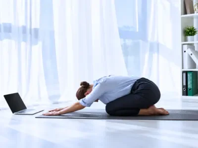 Woman practicing Child's Pose on a yoga mat during a 200 Hour Online Yoga TTC