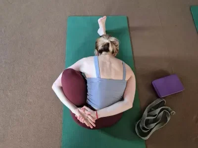 Student practicing a seated yoga stretch on a mat during 200 Hour Yoga Teacher Training